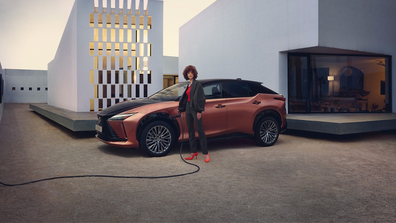 A person stood next to a Lexus and a wall charging box